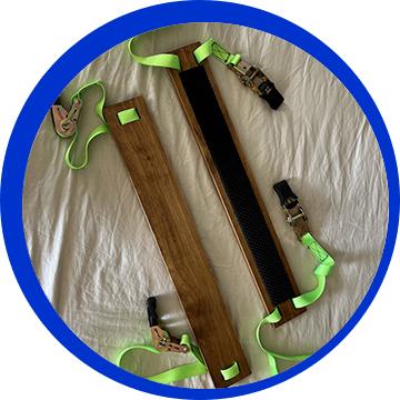 A pair of wooden straps with green handles.